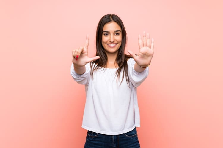 Myths about Addiction and Recovery, pretty young woman signing the number seven with her hands against a pink background - myths